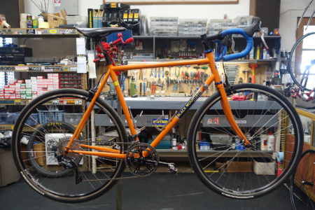 Orange Black Mountain Cycles road bike in bike shop work stand