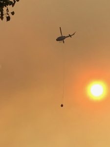 Helicopter flying across smoke filtered sun with water