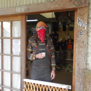 Man at front door of business with bandana mask